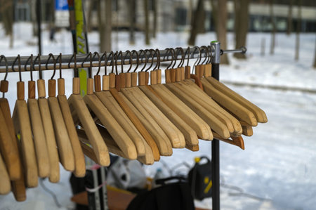 Many wooden hangers on a rod. Store concept, sale, design, empty hangers. Black Friday. Wooden coat hanger clothes. Fashionable different types of hanger. Wood Hangers coat. Blurred focus.の写真素材