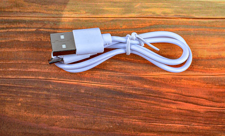 Close-up of a White USB Cable.A white USB type C charger cable, compatible for many devices, wrapped...