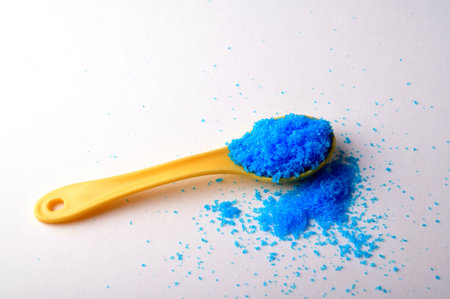 Cupric sulfate in glass bowl, isolated on white background. Bright blue copper sulfate CuSO4, also blue vitriol or bluestone. Salt, used in swimming pools, fireworks and in schools to grow crystals.の写真素材