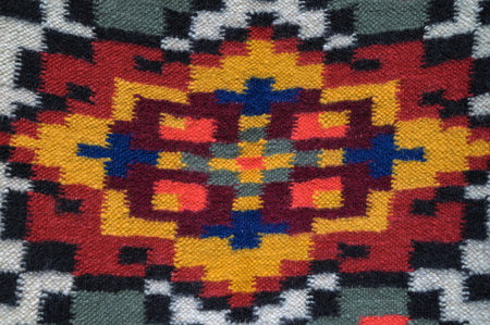 A colorful woven carpet with a traditional geometric pattern that reflects the rich cultural...