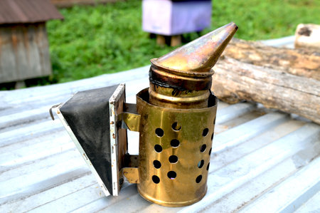 Metal beekeeping smoker used to calm bees during apiary work. Beekeeper tool outdoors, traditional beekeeping and rural agriculture concept.の写真素材