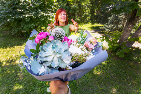 Happy girl. Bouquet as a gift. Red-haired girl receives flowers as a gift. A man's hand with a bouquet. Valentine's Day. Concept March 8の写真素材
