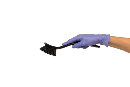 female hand in a purple rubber glove holds a black dishwashing brush with a plastic handle. Isolate...