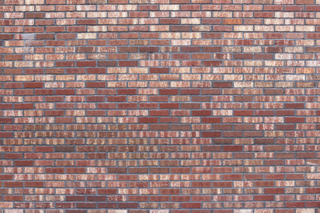 Wall of red-brown brick. Textural background. The facade of the old beautiful building. Different tones of red and orange colorsの写真素材
