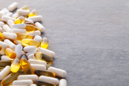 Tablets, pills, capsules, drugs pouring out of white bottle on white background. Sport, healthy lifestyle, medicine, nutritional supplements, people concept - closeup fish oil capsules softgelの写真素材