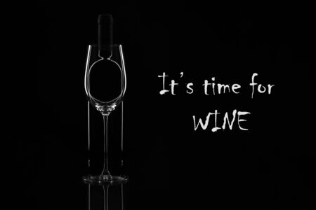 Elegant wine glass and wine bottle on black background. Bottle behind glass. Contour. Horisontal.の写真素材