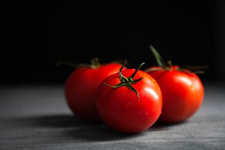 Tomato with drops. Full depth of field. Fresh red ripe tomatoes for use as cooking ingredients in the foreground with copyspace on dark background. Harvesting tomatoes. Top viewの写真素材