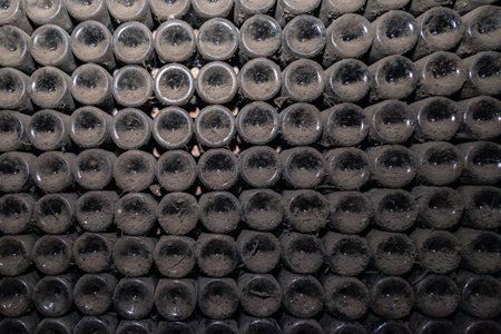 Closeup pattern from bottom of old dark dusty wine bottles in rows in cellar, basement, wine...