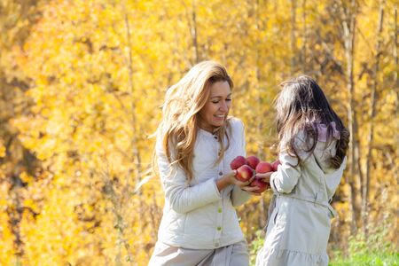 Happy mom and daughter in autumn parkの写真素材