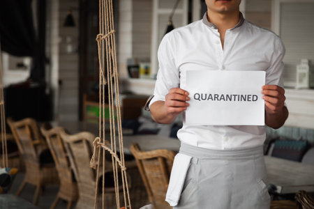 Man in uniform is holding white sheet of paper with word Quarantined