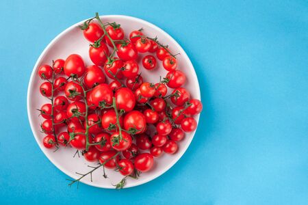 Bunch of bright fresh red cherry tomatoes on round plateの写真素材