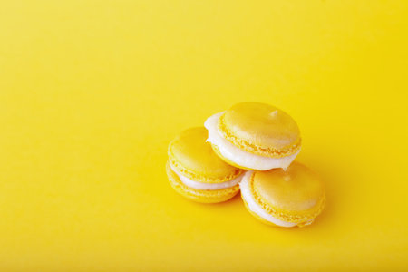 Three yellow lemon macaroon in pile on yellow