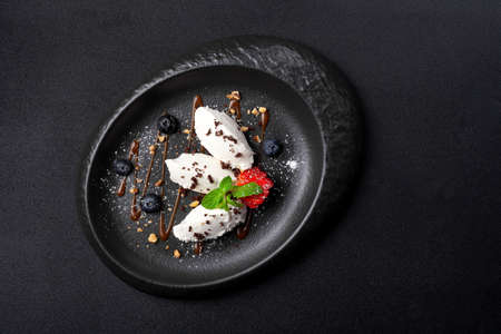 Dessert in oval plate, vanilla ice cream, blueberry, strawberry, caramel sauceの写真素材