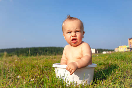 Cute sweet little blonde naked baby sitting in basinの写真素材