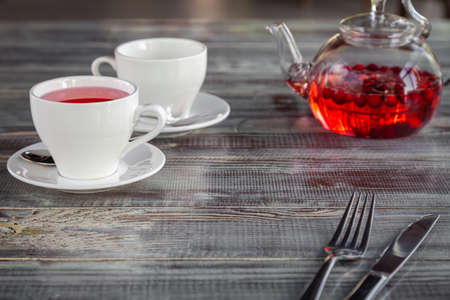 Pink berry red teapot, white cups, cutlery on gray wooden backgroundの写真素材