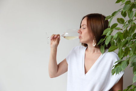 Caucasian brunette girl sommelier drinking white wine from glass