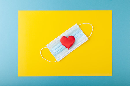 Red hearts and crossed two anti-epidemic blue medical protective masksの写真素材