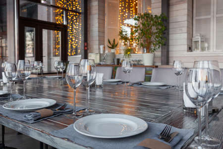 Modern veranda restaurant interior, banquet setting, glasses, platesの写真素材