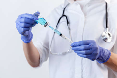 Doctor in gloves filling up syringe from bottle with vaccine, medicineの写真素材