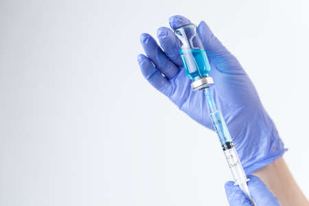 Doctor in gloves filling up syringe from bottle with vaccine, medicineの写真素材