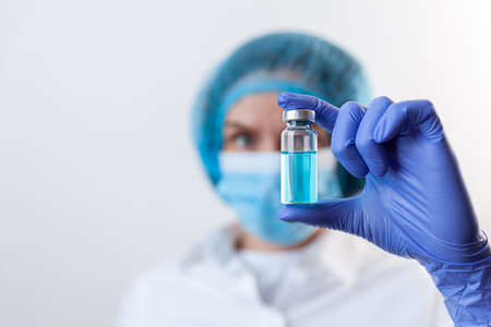 Doctor in gloves and mask holds bottle with vaccine, medicineの写真素材
