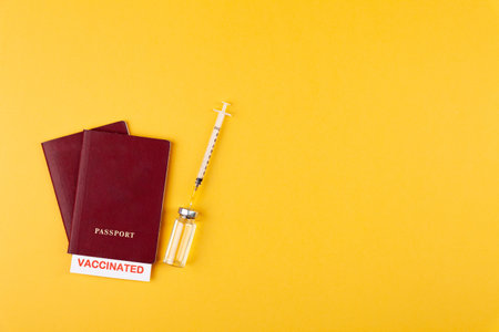 Passports with vaccinated stamp on blank, syringe, bottle with vaccine on yellow background