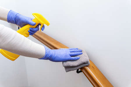Woman hands in gloves cleaning stairs railings with ragの写真素材