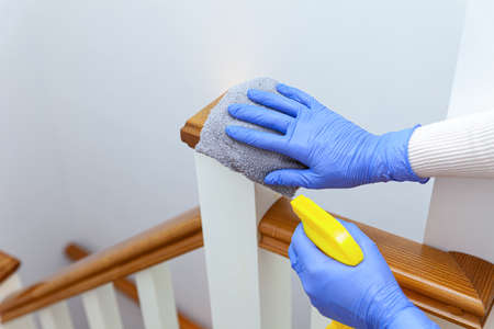 Woman hands in gloves cleaning stairs railings with gray ragの写真素材