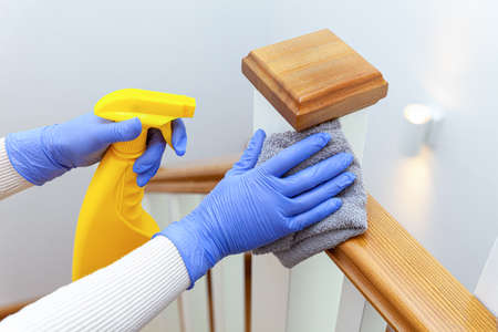 Woman hands in gloves cleaning stairs railings with ragの写真素材