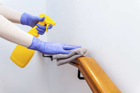 Woman hands in gloves cleaning stairs railings with ragの写真素材
