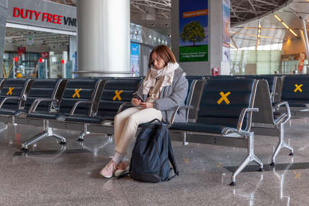 Girl tourist with backpack waiting for flight in airport, horizontal, Russia Moscow Vnukovo 2021-03-01のeditorial素材