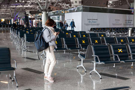 Girl tourist with backpack waiting for flight in airport, horizontal, Russia Moscow Vnukovo 2021-03-01のeditorial素材