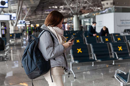 Girl tourist with backpack waiting for flight in airport, horizontal, Russia Moscow Vnukovo 2021-03-01のeditorial素材