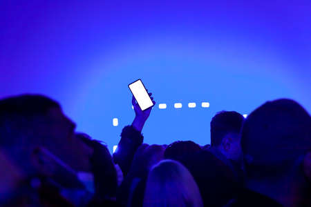Mockup empty white smartphone screen, people in night club party concertの写真素材
