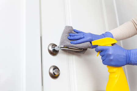 Hands in gloves disinfecting door handle with rag and spray detergentの写真素材