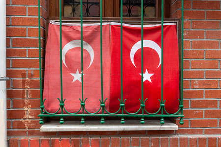 Two waving Turkish Flag in window with grate, brick wallの写真素材