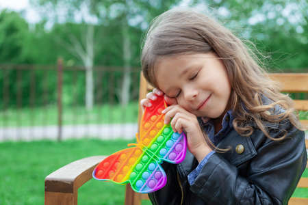 Caucasian little girl playing with pop silicone trendy rainbow color toyの写真素材