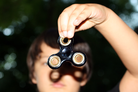 Spinner in the hands of the boyHand spinner or fidgeting spinner rotating on child's hand.の写真素材