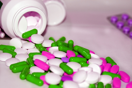 Multicolored tablets and capsules emptying out of the bottle.の写真素材