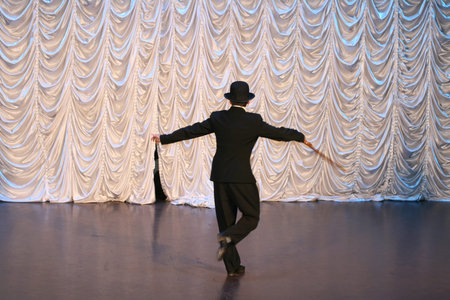 Tap dance with a cane in a black hat. Dance step. A man is dancing on stage.
