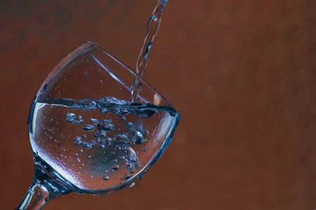 Wine glass with drinking water and bubbles. Red / orange background.の写真素材