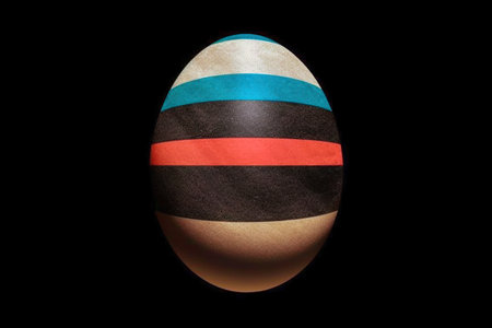 Easter egg with a striped pattern isolated on a black background.の素材