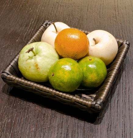 fruit in basket on wooden tableの写真素材