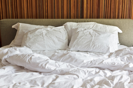 Messy white bed and two pillow, in the morningの写真素材