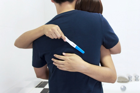 woman with pregnancy test hugging manの写真素材