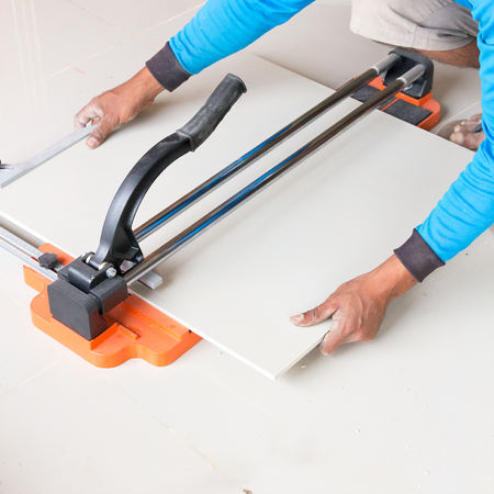 Industrial tiler builder worker working with floor tile cutting equipmentの写真素材