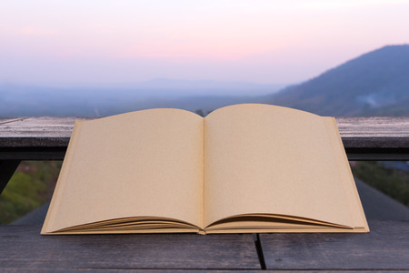 Big brown notebook blank open on terrace with sunset mountain background.の写真素材