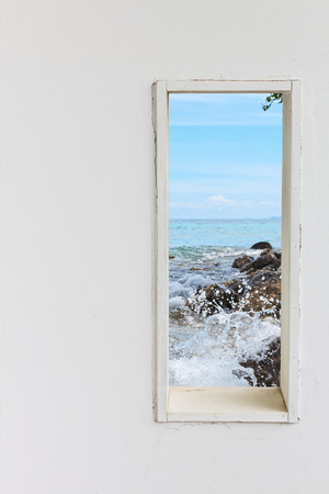 White wall window with sea beach view, vertical landscape concept background.の写真素材