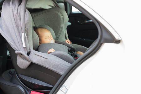 Asian cute one month old newborn baby sleeping in modern car seat. Child new born traveling safety on the road. Safe way to travel fastened seat belts in a vehicle with young kids. Trip with an infant.の写真素材