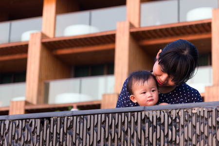 Asian young mother and cute nine month baby enjoy swimming pool, Active healthy playing water in pool at resort.の写真素材